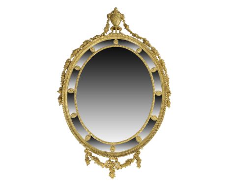 A large English giltwood oval mirror, of Adam style, first quarter 20th century, the moulded gadrooned frame with egg and dar