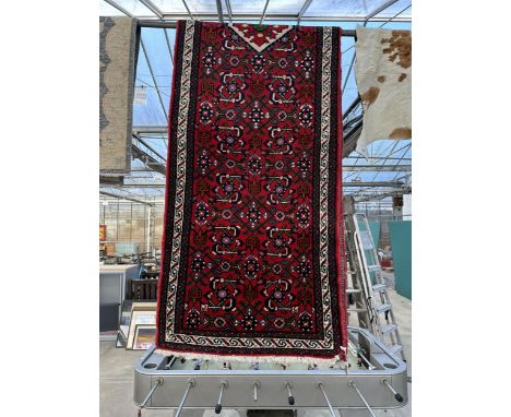 A VINTAGE STYLE RED PATTERNED FRINGED CARPET RUNNER