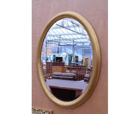 AN OVAL GILT BOMBAY COMPANY WALL MIRROR WITH BEVEL EDGE, 31" X 23"