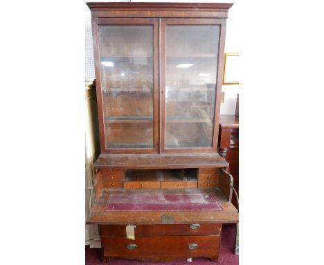 A 19th century oak secretaire bookcase, two glazed doors enclosing adjustable shelves, pull out desk over three drawers, rais