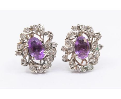 A pair of vintage amethyst and topaz white metal earrings, comprising an oval amethysts claw set to the centre within a borde