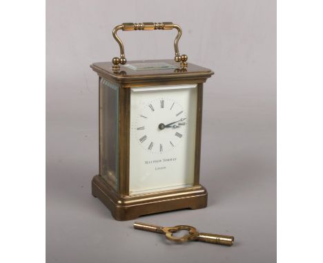 A brass cased carriage clock with platform escapement. Having enamel dial signed Matthew Norman, 14cm.  Sold with key. Runnin