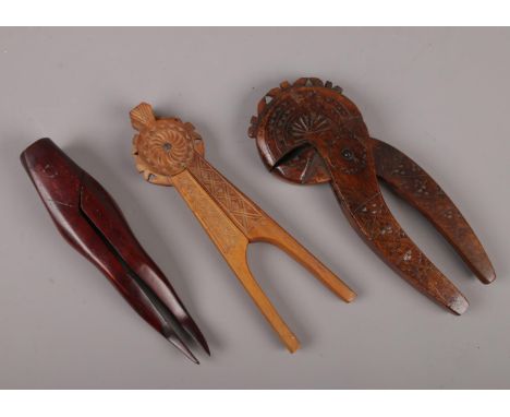A Scandinavian chip carved treen nut cracker, another folk art wooden nut cracker and one formed as a pair of legs.  