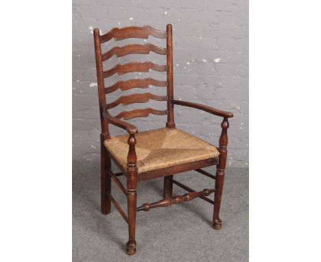 An oak rush seat ladder back kitchen armchair.  