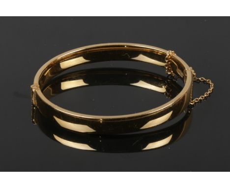 A gold plated bangle with engraved detail. Stamped 1/5 9ct, G. J. Ltd.