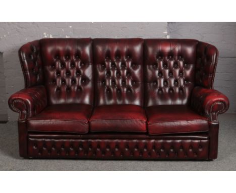 An ox blood leather deep button three seat sofa, along with a matching arm chair.  