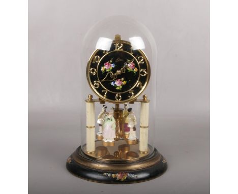 A Kern torsion clock under glass dome. The pendulum disc is surmounted by four china figures. With ebonized dial and plinth p