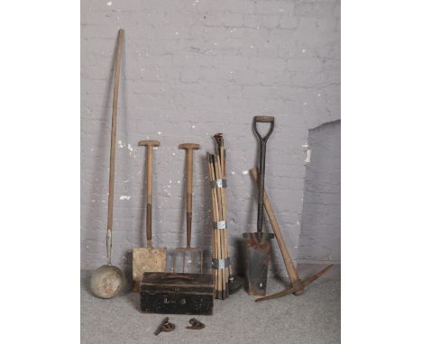 A collection of tools including pick axe, post spade, drain rods and ladle etc.  