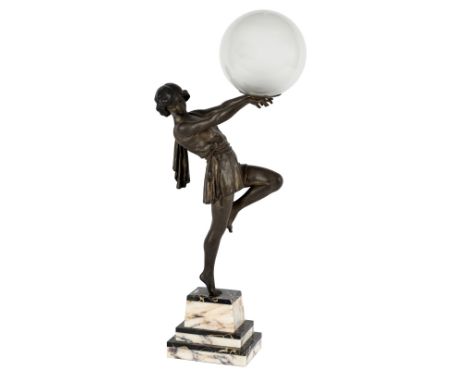 An Art Deco style lamp in the form of a metal figure of a dancer, poised on one leg and holding aloft a globe, on a variegate