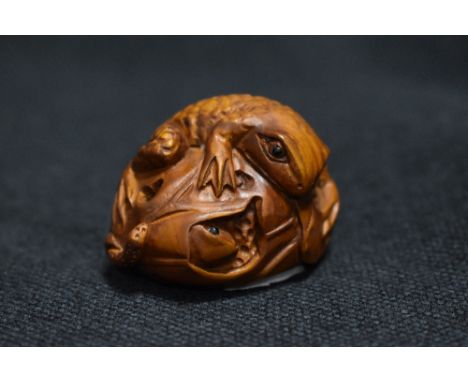 An early 20th century Japanese Netsuke carved wood sculpture of a frog with lily leaf wrapped around a smaller frog