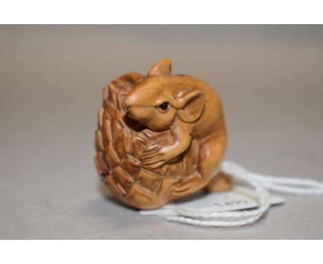 An early 20th century Japanese Netsuke carved as a mouse holding onto a Conifer cone