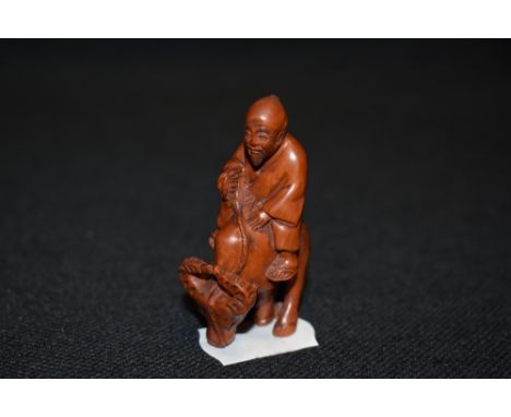 An early 20th century Japanese carved wood Netsuke of a nomad riding an Ox