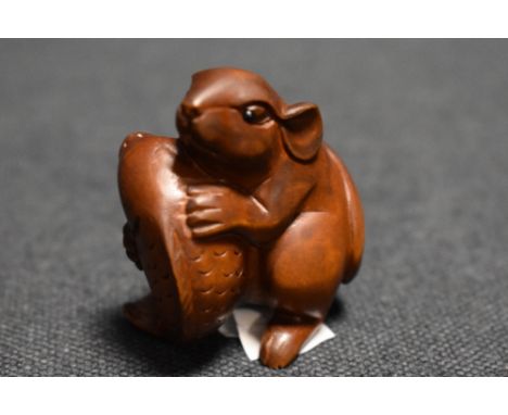 An early 20th century Japanese carved wood Netsuke of a Rat holding a small Carp fish