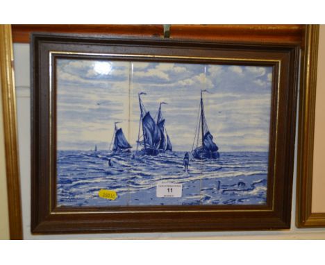 A Delft blue and white pottery tile picture depicting a beach scene with fishing boats, signed