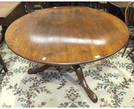 A Georgian-style quality oak circular dining table on turned column and tripod supports, 135cm diameter.