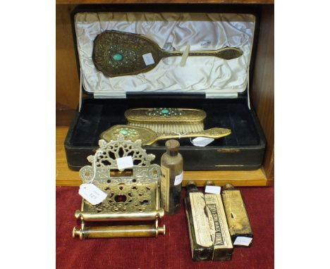 A three-piece gilt metal decorated cased dressing table set, comprising of hair brush, clothes brush and hand mirror, a Victo