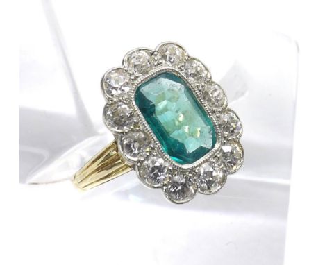 Emerald and diamond cluster ring, the central emerald in a surround of twelve round old-cut diamonds in yellow and white gold