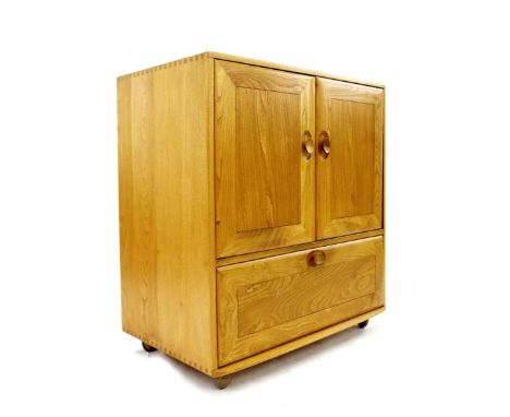Ercol light elm television/side cabinet, fitted with two sliding cupboard doors over a fall-front drawer enclosing a slide wi