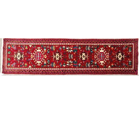 A 20th century North Wester Persian Heriz runner floor carpet rug. The rug having a reg ground with geometric medallions to c