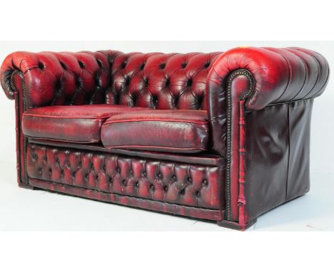 A 20th century Chesterfield two seater sofa settee leather sofa in oxblood red colour with button back and scrolled armrests.