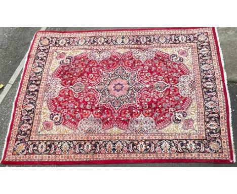 A 20th century Iranian Heriz Tabriz floor carpet rug. The carpet having a central black medallion with herati on red ground w