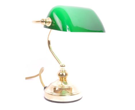 A 20th century miniature bankers lamp having a green cased glass shade over a brass frame on circular base. Measures 25cm tal