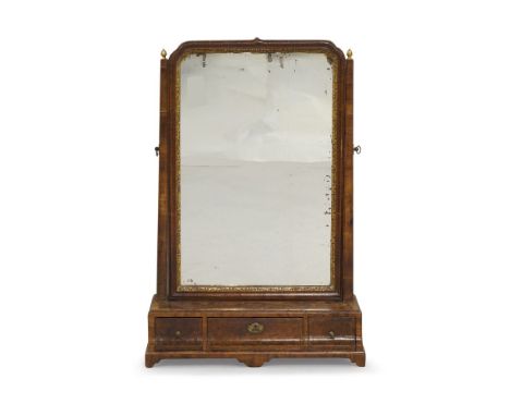 A George III walnut dressing mirror, the shaped frame flanked by gilt metal finials, three drawers, shaped apron, raised on b