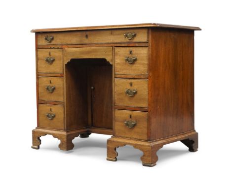 A George III mahogany kneehole desk, with frieze drawer above recessed cupboard flanked by six pedestal drawers, raised on br
