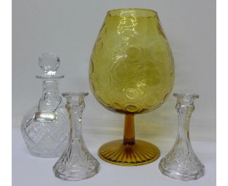 A glass decanter with a silver port label, a pair of candlesticks and an amber coloured glass vase