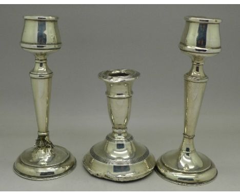 A pair of silver candlesticks and one other candlestick, a/f