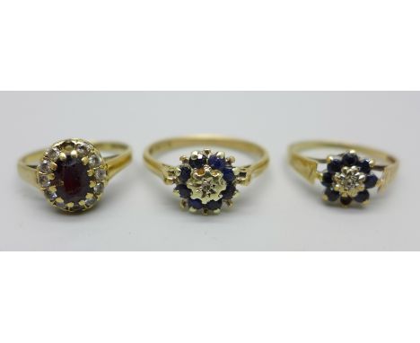 Three 9ct gold cluster rings, one set with a garnet and white stones, and two others with blue stones, two have stones missin