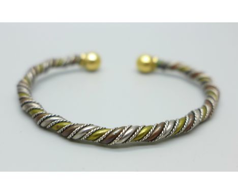 A torc bangle with yellow metal finials 