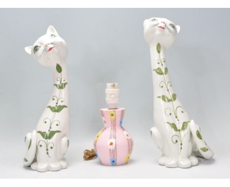 A pair of vintage retro Italian cat figurines of elongated stylised form being hand painted with green floral sprays together