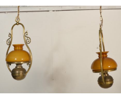 A contemporary pair of antique style large brass hanging lantern of oil lamp type with modern electric wiring. The brass rese
