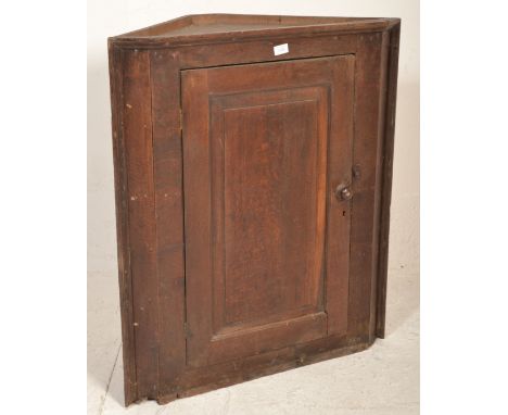 A George III 19th century country oak hanging corner cabinet. Full length fielded panel door with shelves to the interior. Me