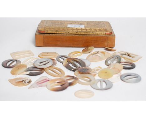 A collection of mother of pearl belt buckles including round, oval and rectangular shaped buckles set within a wooden box wit