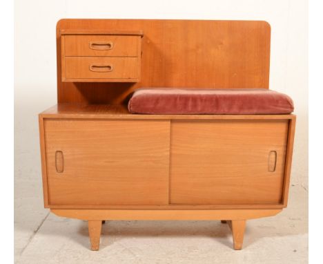 A retro mid century teak wood telephone table with velour pad seat over sliding door cupboard and tapering legs. Finished wit