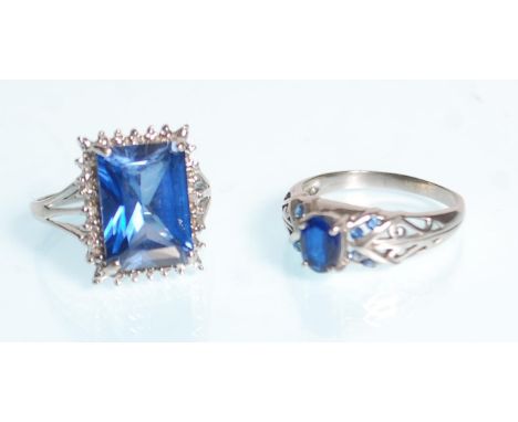 A large 9ct white gold ladies dress ring set with a large central square cut blue stone raised on a split shoulders. Stamped 