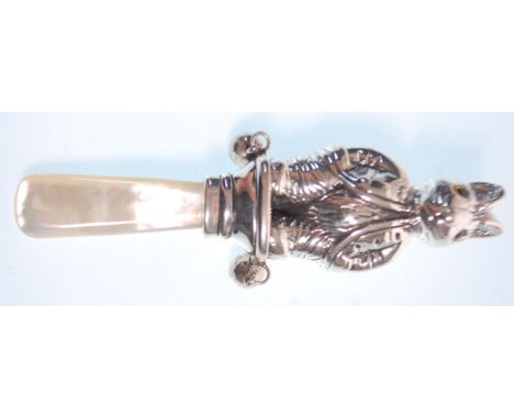 A stamped sterling silver rattle in the form of a rabbit having yellow glass eyes on a mother of pearl handle. Measures 9cm. 