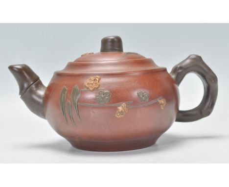 A Chinese Yixing teapot having bamboo style handles and spout, the body having raised applied floral decoration glazed in yel