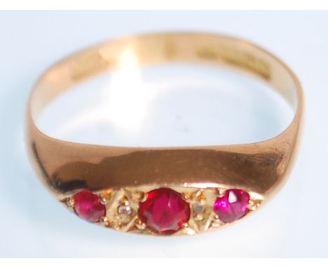 A hallmarked 18ct yellow gold&nbsp;gypsy ring set with three round faceted cut red stones with white stone spacers. Hallmarke