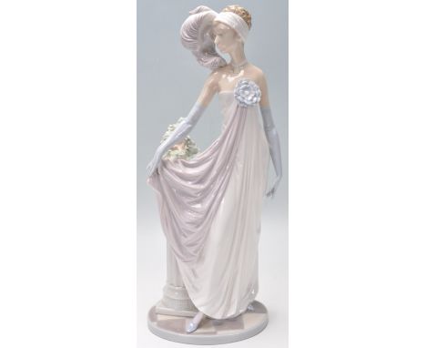 A Lladro porcelain figurine in the form of a 1920's flapper girl modelled with a feather headdress stood by a plant jardinier