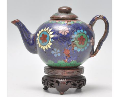 A 19th Century Chinese miniature cloisonne teapot with floral and geometric patterns on a dark blue ground. Raised on a scrol