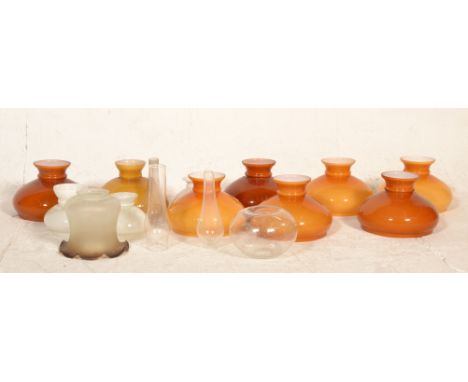 A collection of vintage 20th century glass oil lamp shades. To include amber and white glass shaped examples, clear glass exa