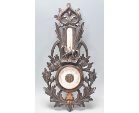A late 19th / early 20th stained oak carved Black Forest aneroid barometer with central dial and milk glass thermometer above
