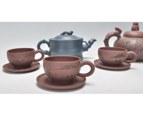 A Chinese Yixing clay teapot having carved decoration of a seated male figure with character marks to the verso, the handle f