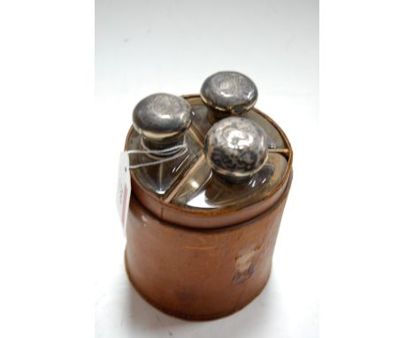 An Edwardian leather cased three flask hunting set each with silver tops (heavily dented lacking lid)