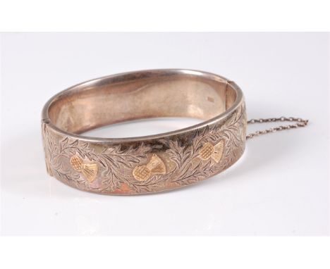 A silver hinged bangle by Charles S Green &amp; Co Ltd, the 18mm wide bangle half set with thistles in yellow metal with engr