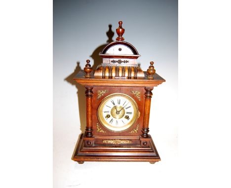 A late 19th century continental beech cased mantel clock having an enamelled chapter ring with Roman numerals and eight day m