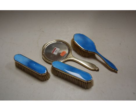 A George V silver and blue guilloche enamelled four piece dressing table set. Damage to the tip of mirror handle.Otherwise en